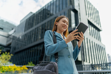 Young Asian Businesswoman Using Digital Tablet While On The Way To The Office In The Morning
