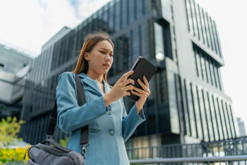 Fototapeta premium Young Asian Businesswoman Using Digital Tablet While On The Way To The Office In The Morning