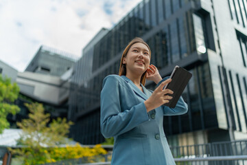 Fototapeta premium Young Businesswoman Using Digital Tablet In Front A Modern Office Building in a Financial District