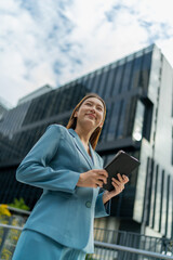 Fototapeta premium Young Businesswoman Using Digital Tablet In Front A Modern Office Building in a Financial District