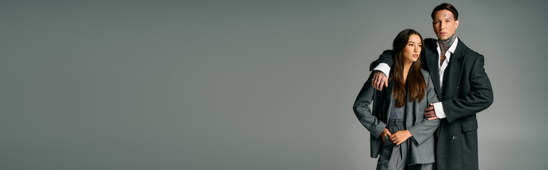 A young attractive couple showcases their chic fashion sense while standing together.