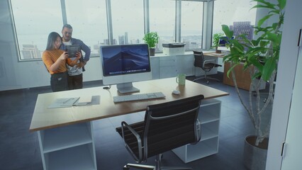 Diverse team of creative designers uses digital tablet computer and augmented reality AI interior design software to build office room. 3D graphics of furniture and digital equipment. VFX animation.