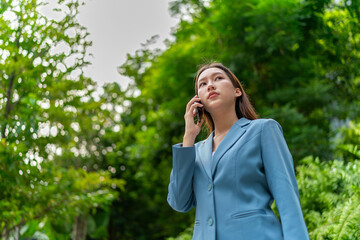 Young Businesswoman In Blue Suit Using Phone Amid Greenery of A Park In The City