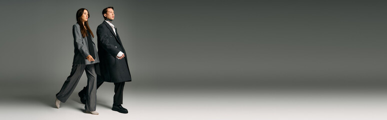 A young couple strolls elegantly in fashion forward attire within an artistic setting.