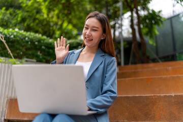 Asian Woman Sitting In A Garden and Using Laptop