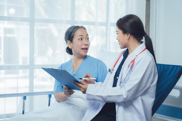 Doctor and Patient Consultation:  A friendly female doctor sits beside her mature Asian patient,...