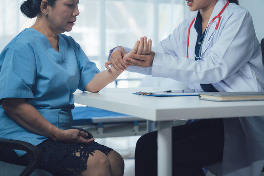 Doctor examining senior patient's wrist 