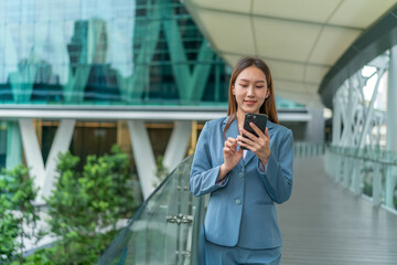 Young Businesswoman In Blue Suit Using Phone Outdoor In Front A Modern Office Building In A Business Financial District