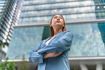 Confident Young Businesswoman With Laptop Bag In Front a Modern Office Building in a Financial Business District