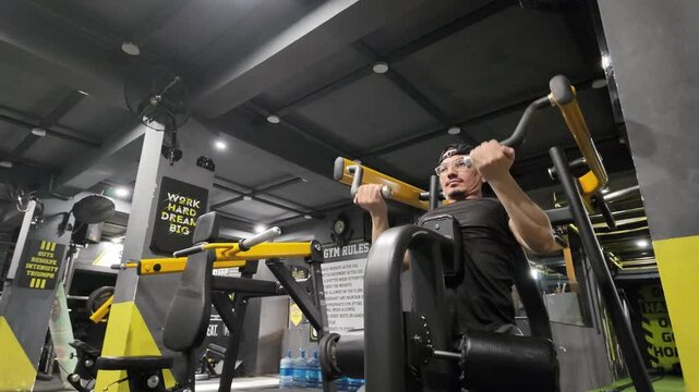 Young, Strong Bodybuilder Doing Leverage Machine Pulldown on Machine for Intense Lower Back Training in the Gym, Close-Up View