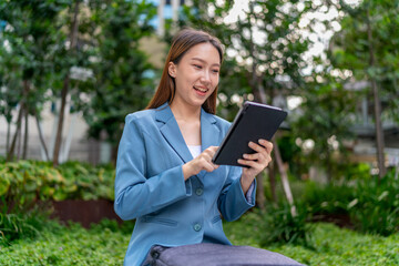 Fototapeta premium Young Asian Businesswoman Using Digital Tablet Outdoor In Front Modern Office Building