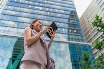Fototapeta premium Asian Businesswoman Using Tablet In Front of A Modern Office Building In the Financial District