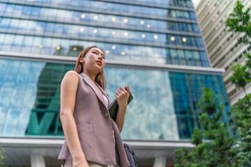 Asian Businesswoman Using Tablet In Front of A Modern Office Building In the Financial District