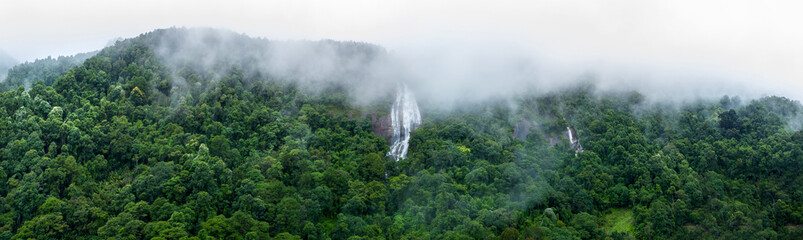 Aerial view of beautiful waterfall village in the lush green rain cloud and foggy cover tropical...