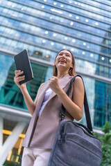 Young Asian Woman Using Tablet In Front A Modern Glass Office Building in Downtown Financial District