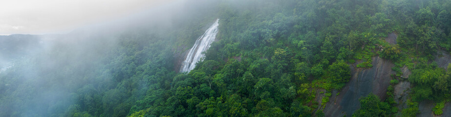 Aerial view of beautiful waterfall village in the lush green rain cloud and foggy cover tropical...