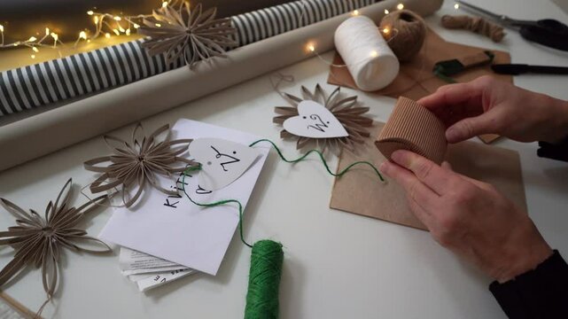Gift wrapping a brown cardboard pillow box for Christmas by caucasian woman