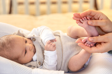 Parent holding in the hands feet of newborn baby. Mom holding baby feet.