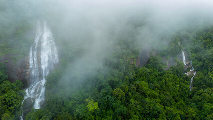 Aerial view of beautiful waterfall village in the lush green rain cloud and foggy cover tropical...
