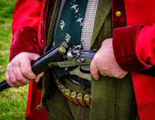 Open double barrelled side-by-side loaded shotgun held in both hands by a shooter on a driven shoot