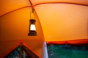 antique lamp Light inside the camping tent at night in the pitch dark forest, selective focus, soft...