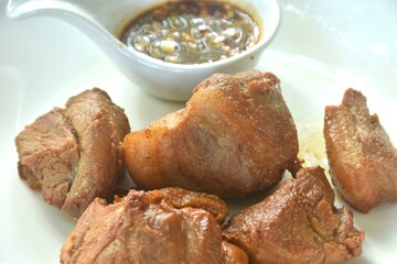 fried crispy slice fat pork in fish sauce on plate dipping with chili sauce