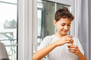 Delicious snack, fast food, junk food. A little happy and cheerful boy is eating French fries while...