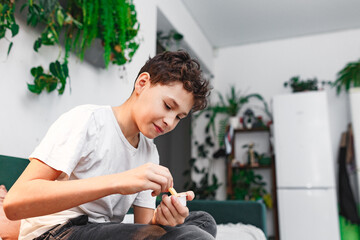 Delicious snack, fast food, junk food. A little happy and cheerful boy is eating French fries while sitting on sofa. 