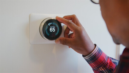Close Up Of Senior Man Setting Digital Smart Heating Thermostat At Home