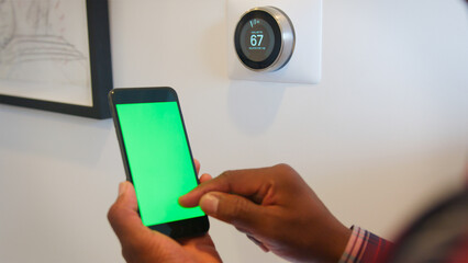 Close Up Of Man Setting Smart Heating Thermostat Using Green Screen Mobile Phone App