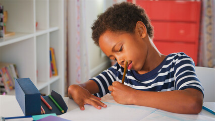 Young Boy Sitting At Desk In Bedroom At Home And Drawing
