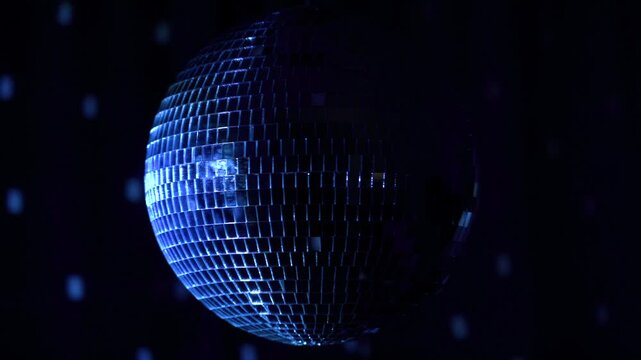 Dazzling reflections from a spinning disco ball create a vibrant atmosphere in a dimly lit dance hall during a lively event