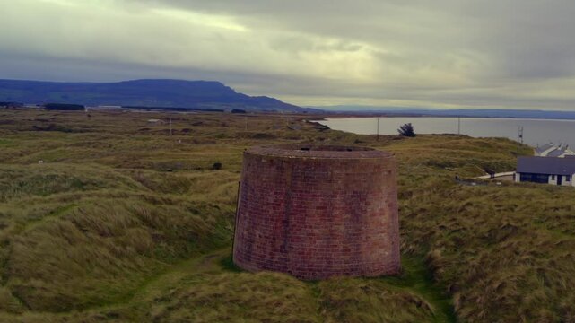 Aerial orbit around Magilligan Martello Tower, showcasing the surrounding landscape