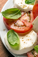 Insalata caprese, un classico antipasto della tradizione italiana composto da mozzarella e pomodoro fresco, conditi con olio extravergine di oliva e basilico 