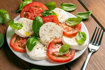 Insalata caprese, un classico antipasto della tradizione italiana composto da mozzarella e pomodoro fresco, conditi con olio extravergine di oliva e basilico 