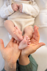 Parent holding in the hands feet of newborn baby. Mom holding baby feet.