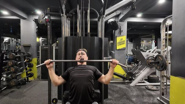 Moving Top View of Handsome Man Performing Front Lat Pulldown on Gym Machine, Targeting Back Muscles and Focusing on Back Development During Workout 