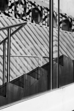 Reflection of a geometric staircase in sleek, modern glass creating a striking symmetrical view representing contemporary architectural harmonies and abstract ideas.
