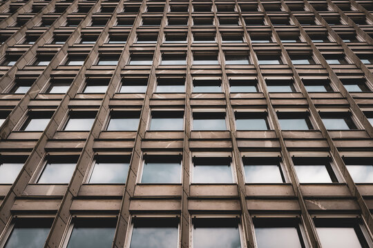 simetrical photography of Big concrete building of offices with many rectangular windows reflecting the Sky 