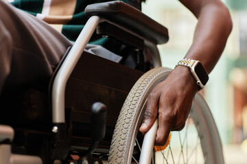 Close up of African American man with disability using wheelchair with focus on hand at wheel, copy...