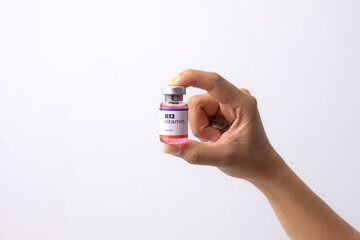 a hand holds a bottle of b12 vitamins in her clinic room. medical concepts