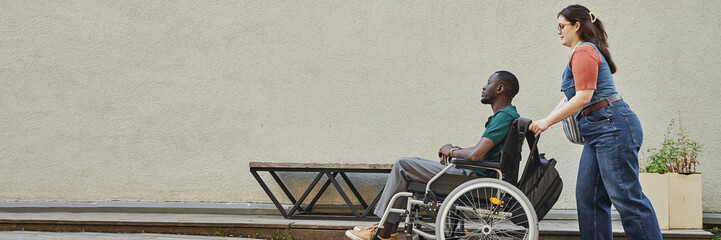 Minimal full length shot of young African American man with disability moving up on ramp with...