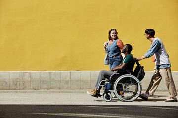 Vibrant wide angle view at inclusive group of friends with young African American man using...