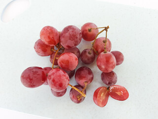 red grapes on a wooden plate and on a cutting board on a white background