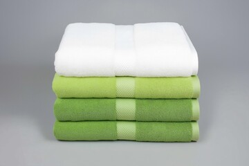 Green and white towels stacked in even layers on a gray surface, showcasing crisp and soft textures