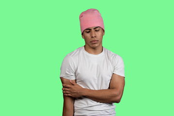 Young latino man wearing pink beanie and white t-shirt on green background contemplating