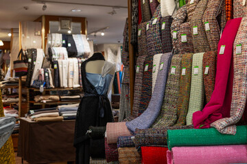 Fototapeta premium Large selection of fabrics in the store. Luxury material for sewing women's clothing.