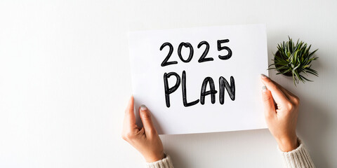 New year plan 2025 and resolutions concept. A person holds a sign that reads "2025 PLAN," suggesting a focus on future goals and strategic planning.