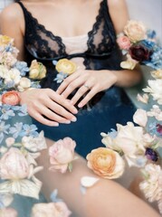 A woman in lace attire amidst vibrant flowers, with hands gently resting on their lap, creating an elegant and delicate aesthetic scene.  concepts of beauty, serenity, and fashion