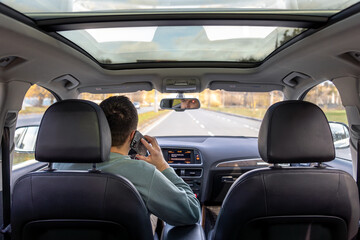 A young man drives a car. A young man drives a car and talks on the phone.